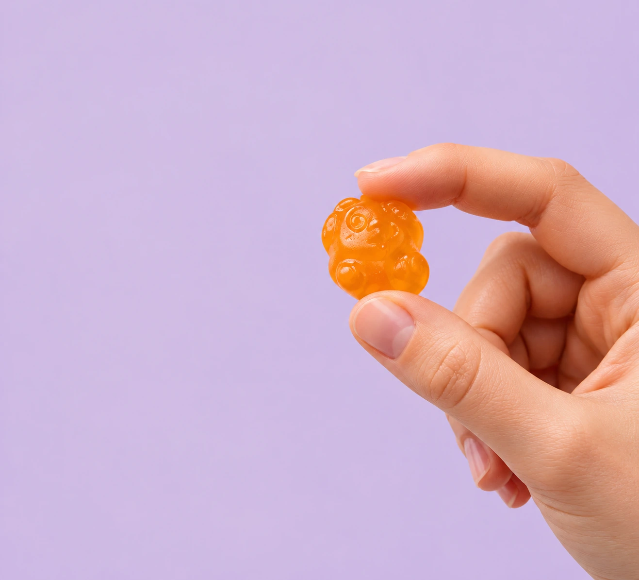 Närbild av en hand som håller en orange gummy
